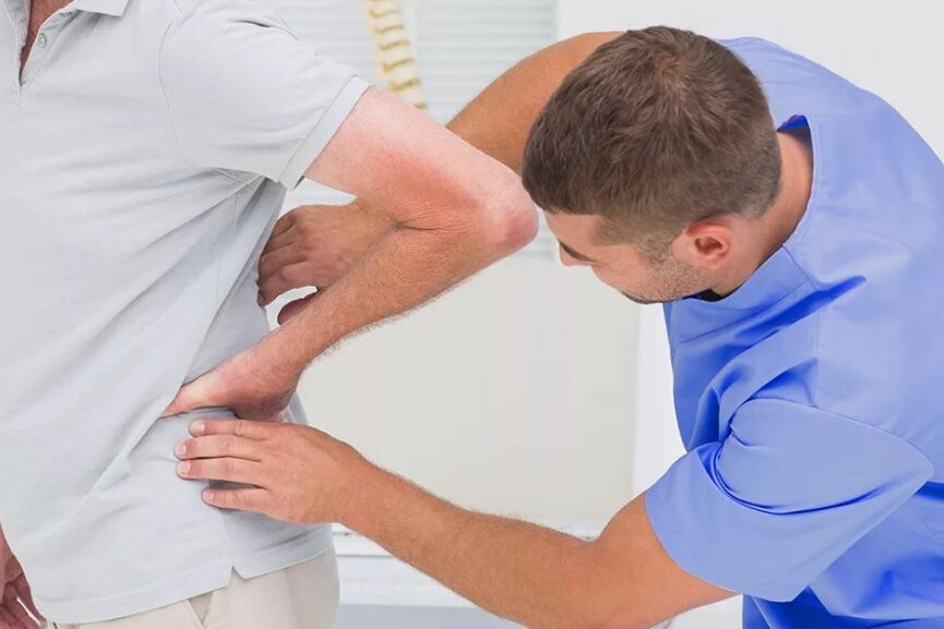 A patient with pain in the lower back pain during a diagnostic examination by a doctor